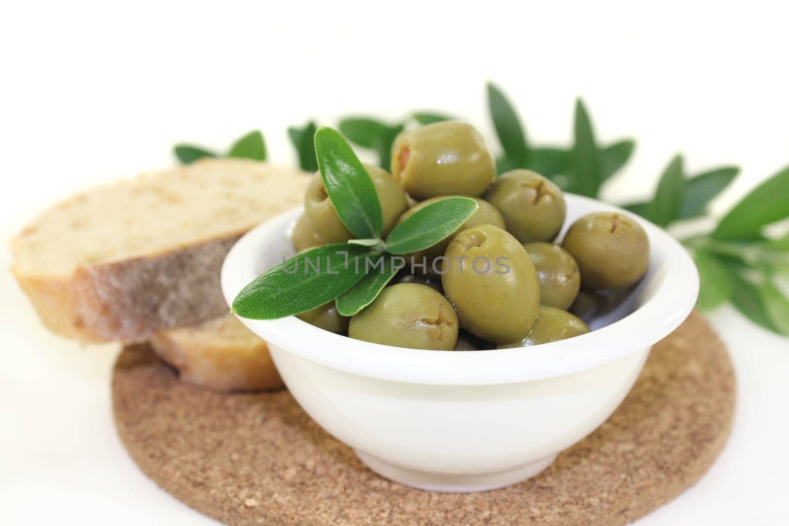 green olives and olive branch in a white bowl