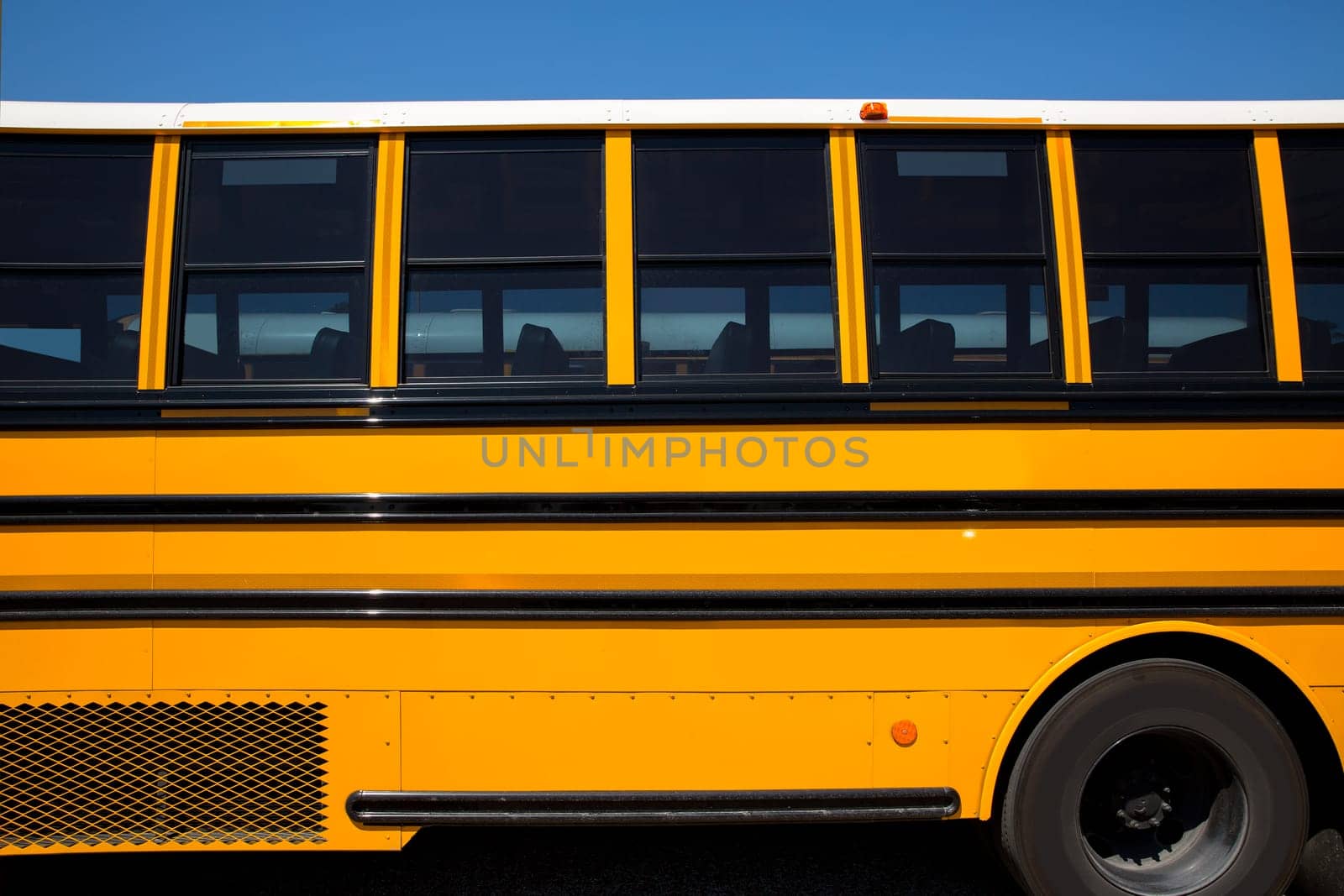 American typical school bus side view on blue sky day