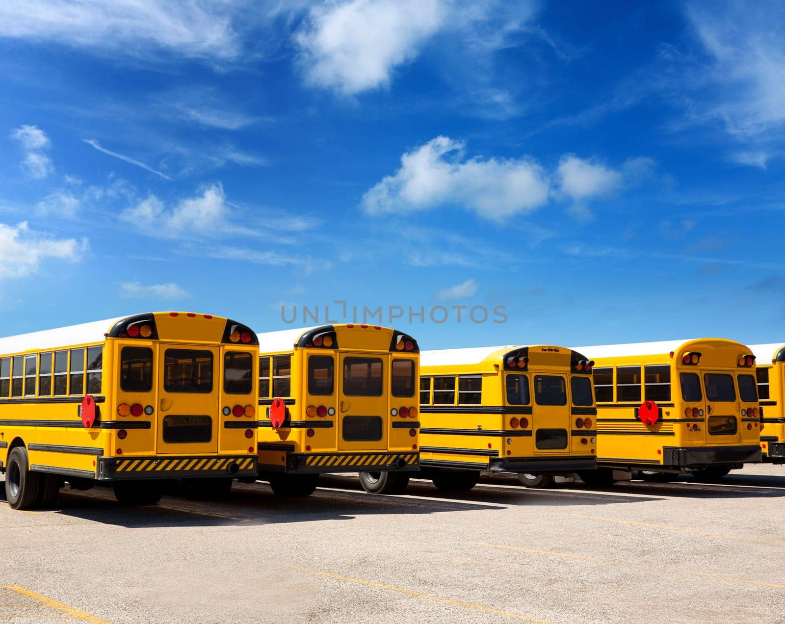 American typical school bus rear view in a row under blue sky day