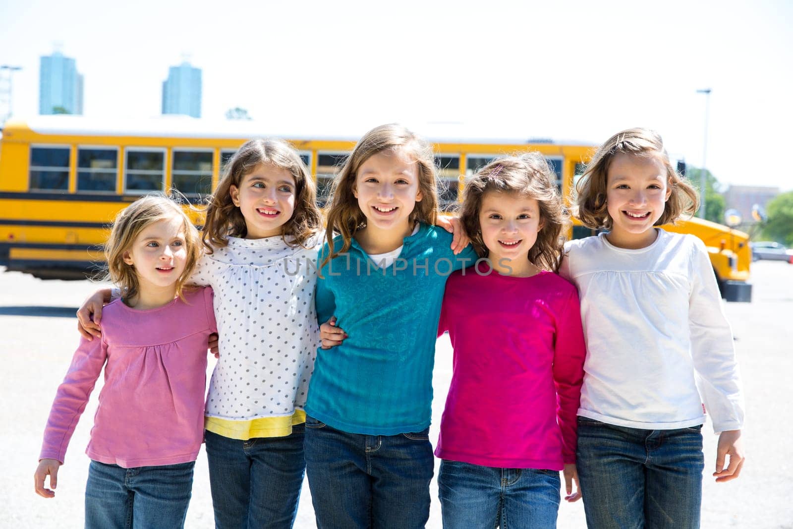 school girls friends sisters in a row walking from yellow school bus lot