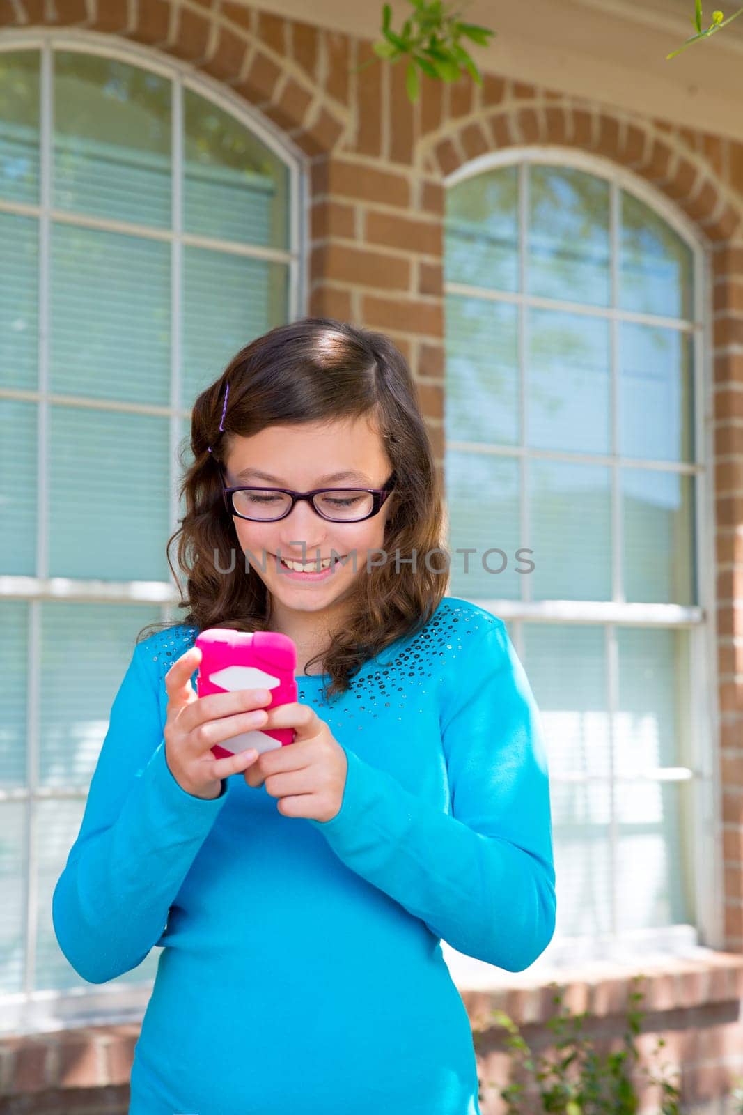 Teenager girl with glasses playing with pink smartphone smiling