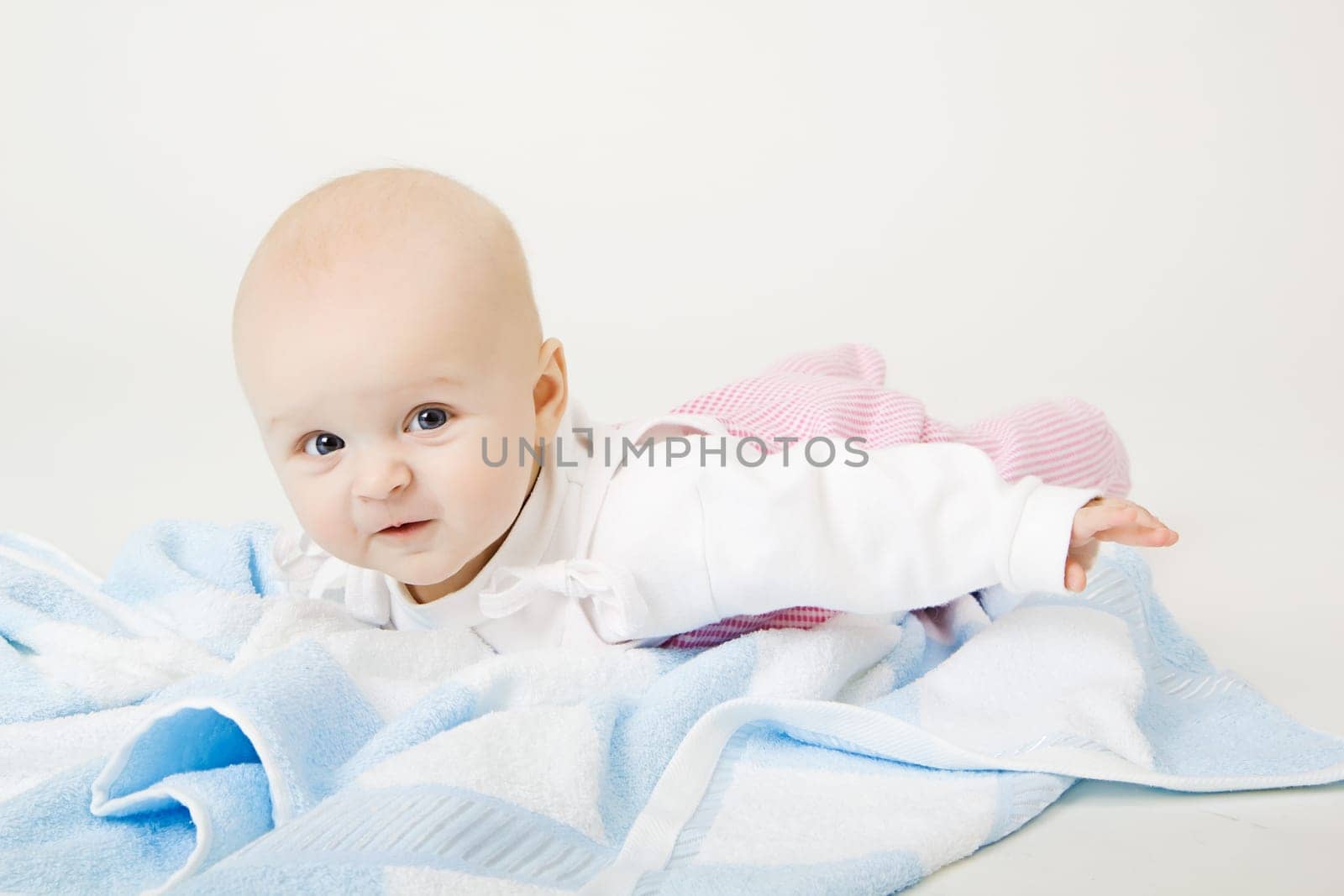 lovely blue-eyed baby with blue towel on the floor