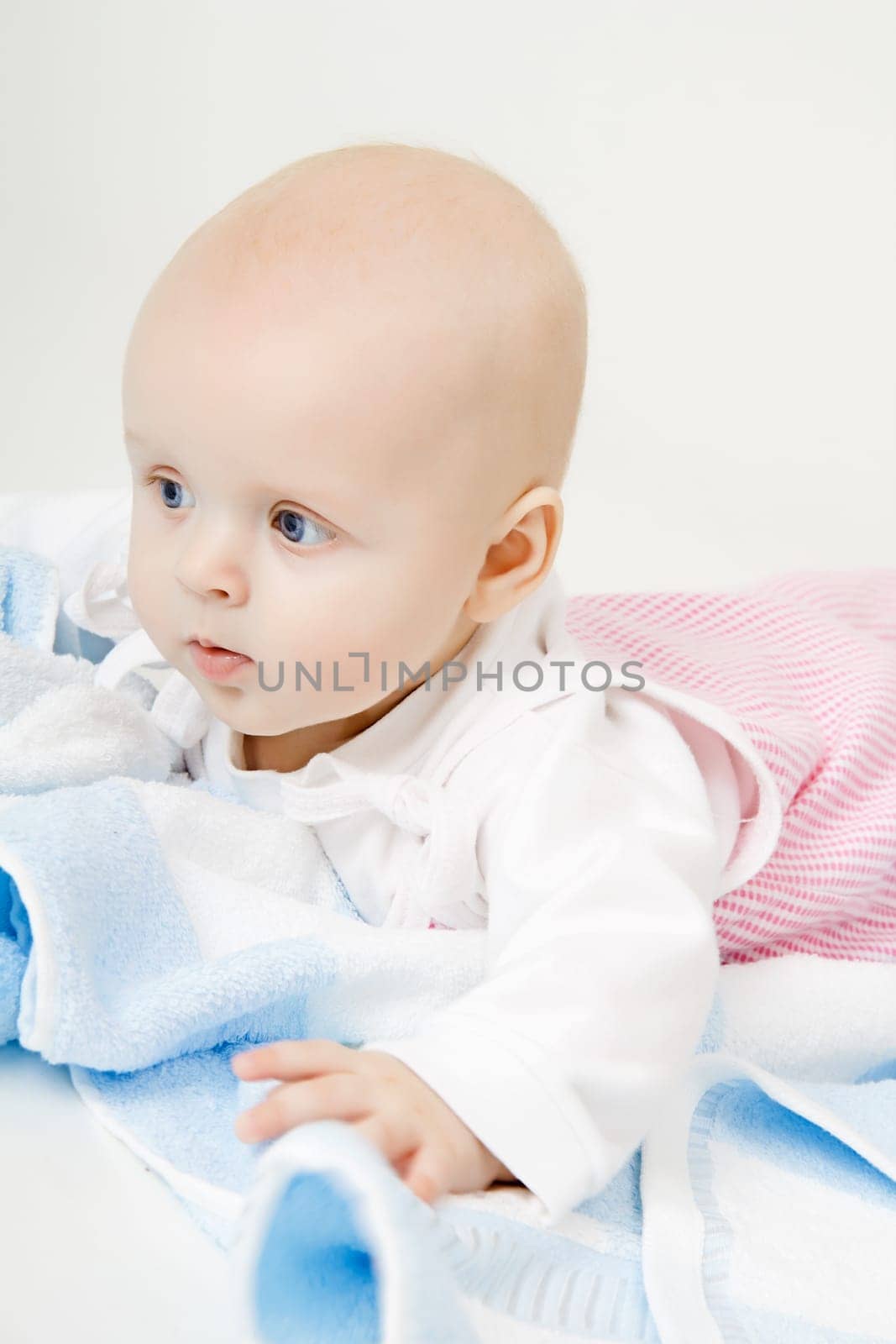 lovely blue-eyed baby with blue towel on the floor