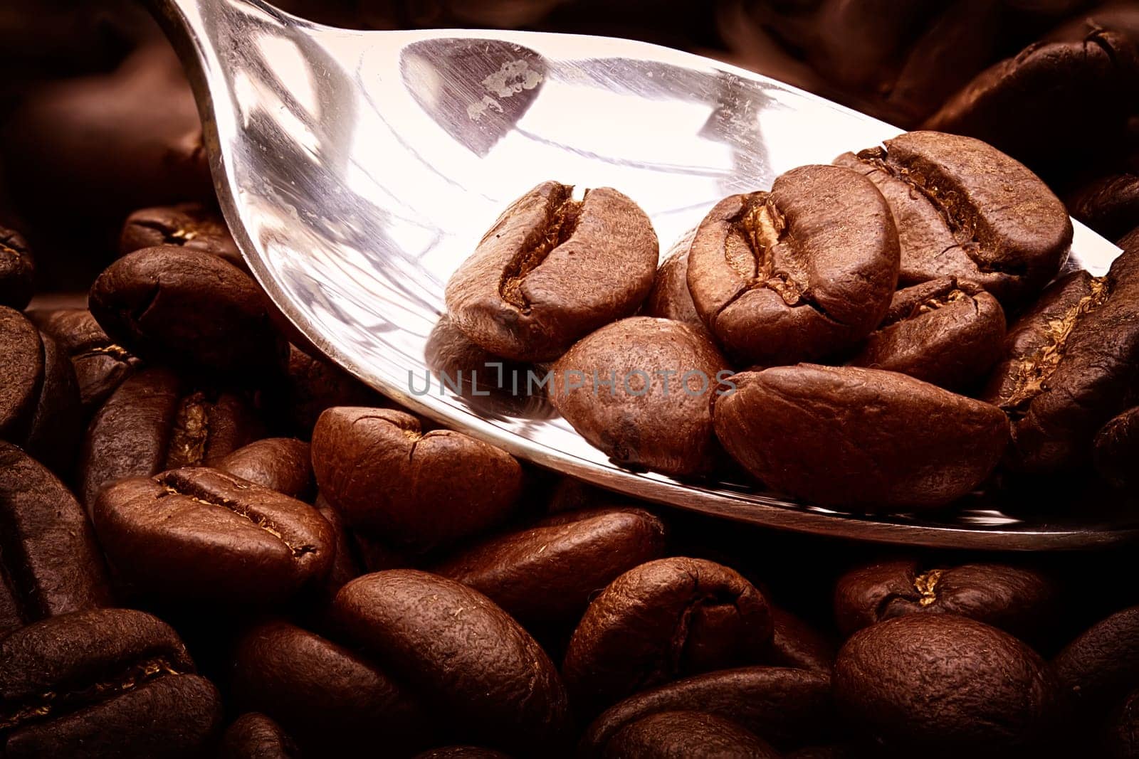Coffe beans on a chrome teaspoon close up