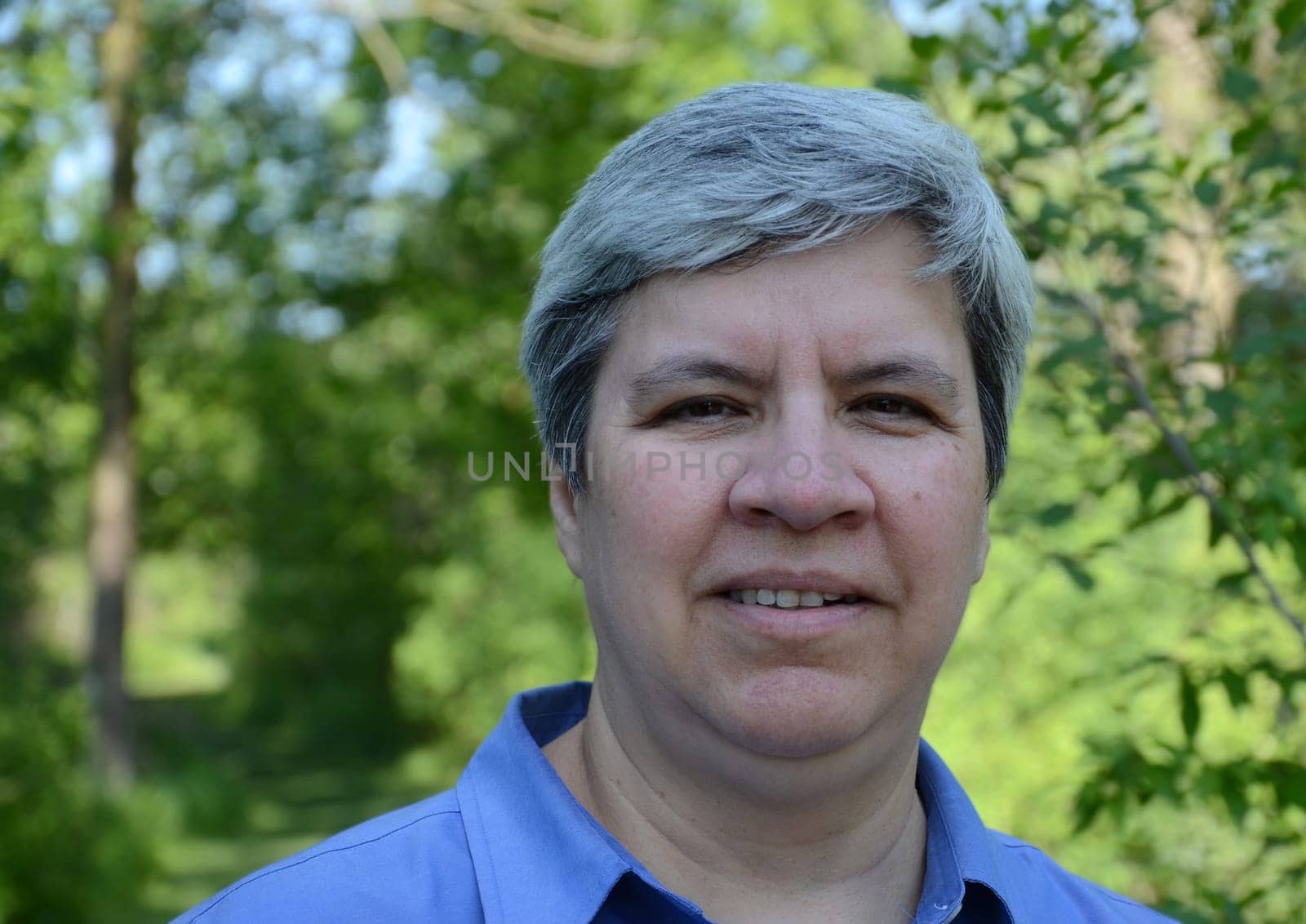 Close up of middle aged woman looking directly at camera, in garden