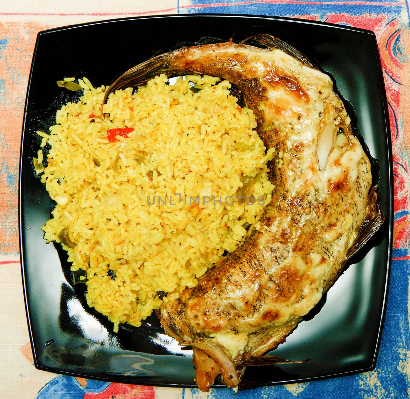 rice side dish with the fried fish on a black square plate