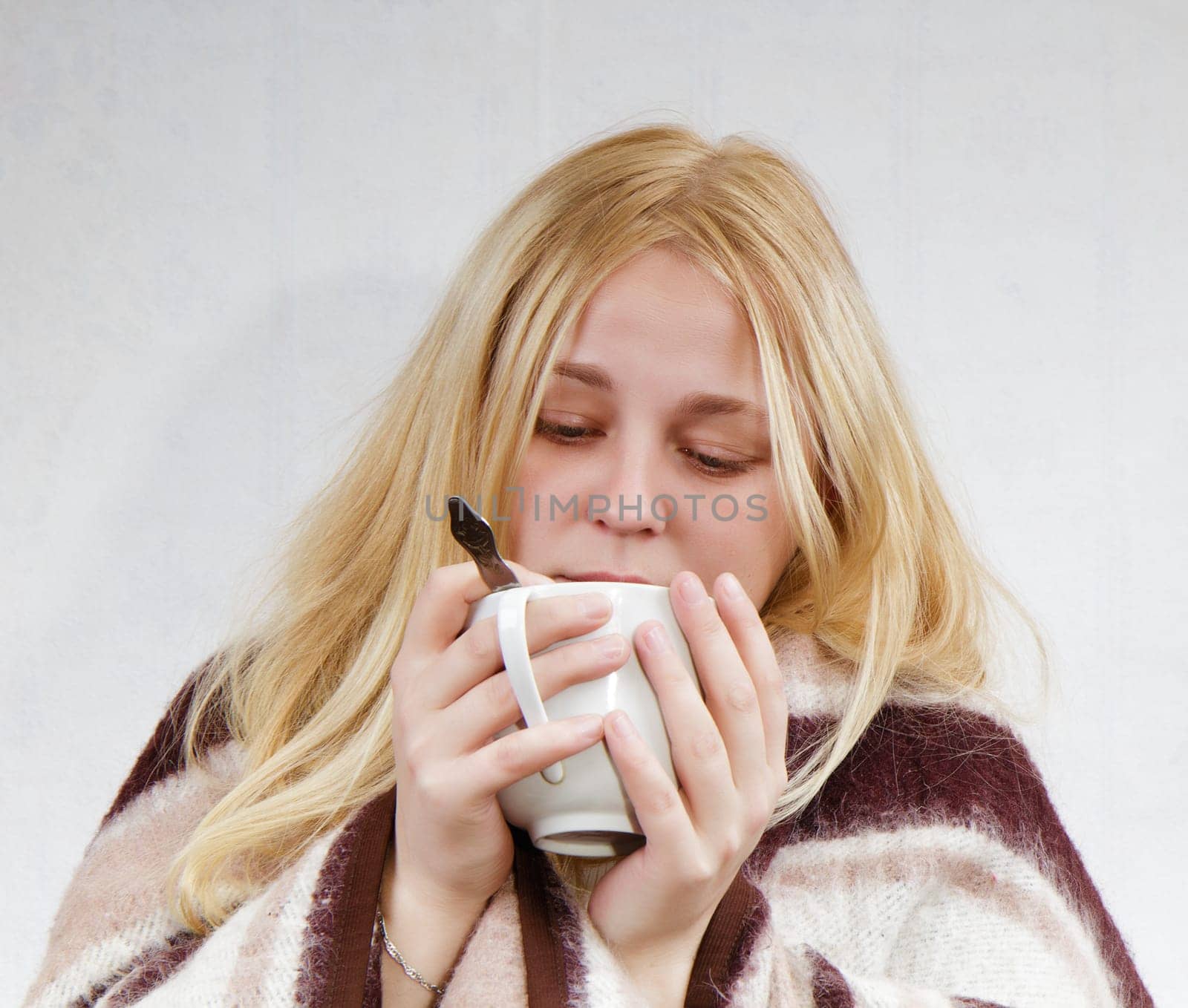 girl with a cup wrapped in a blanket. white background