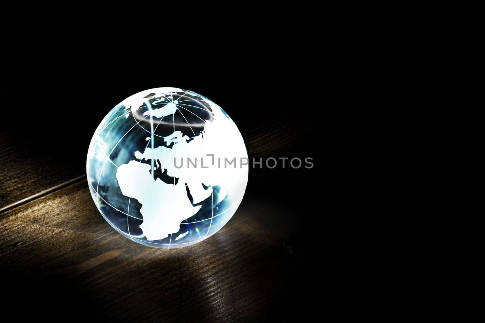 Blue glass earth globe on a wooden table with light