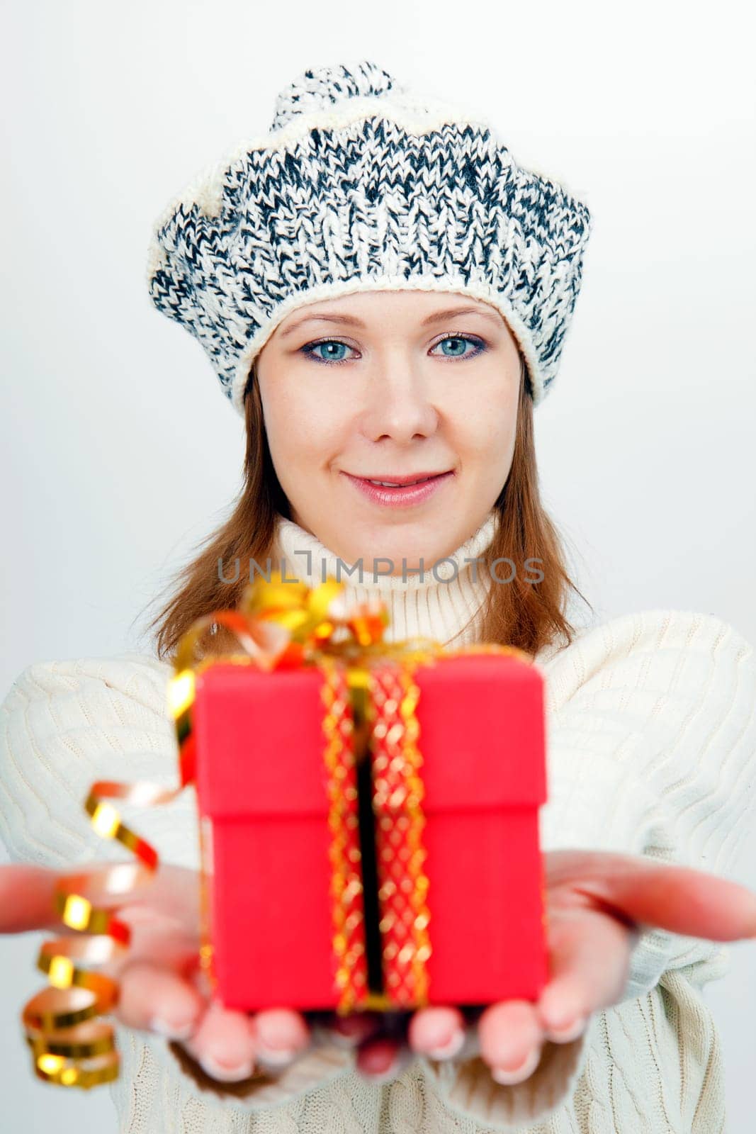 Attractive girl in winter hat gives a wrapped gift