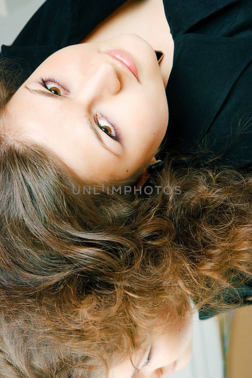 Attractive brunette curly girl lies on a mirror