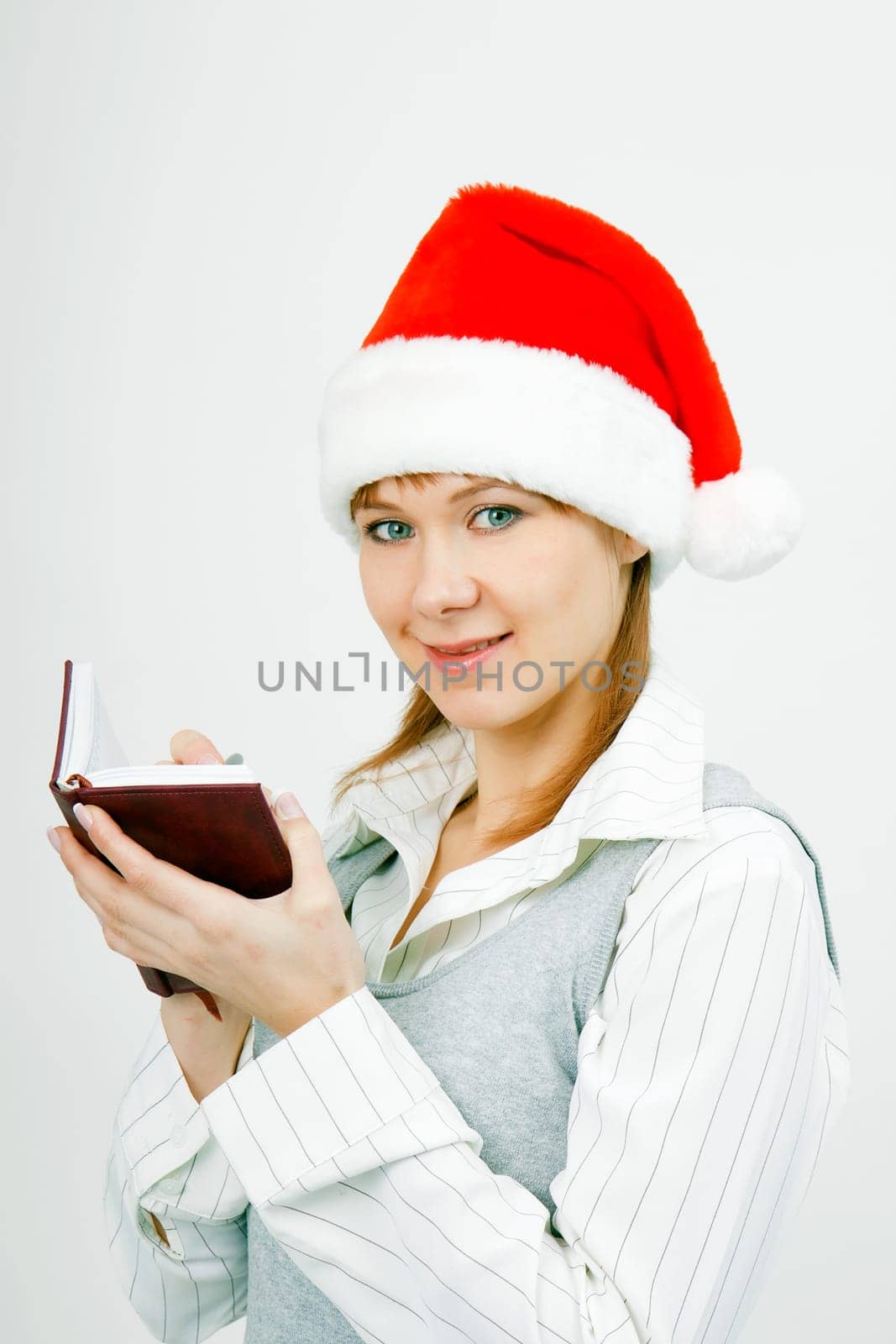 Attractive young girl with a notebook in santa hat