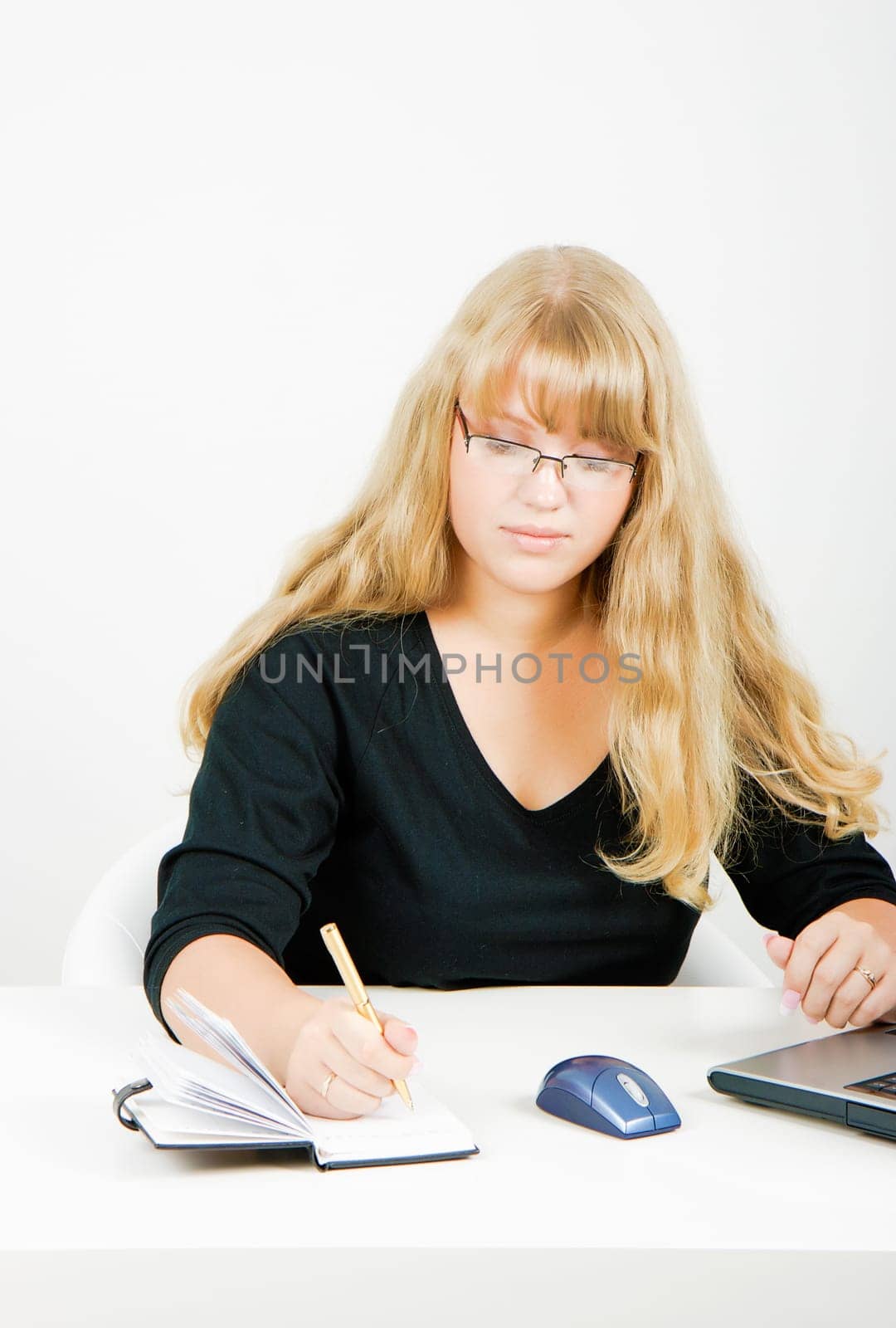 blonde girl with glasses writes in a notebook