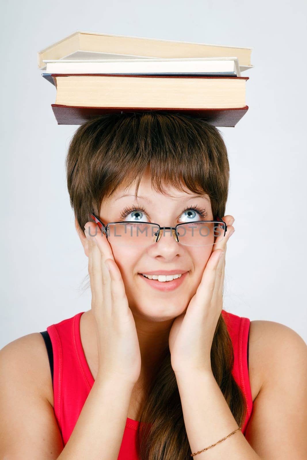 girl in glasses with the books on head on an isolated white background