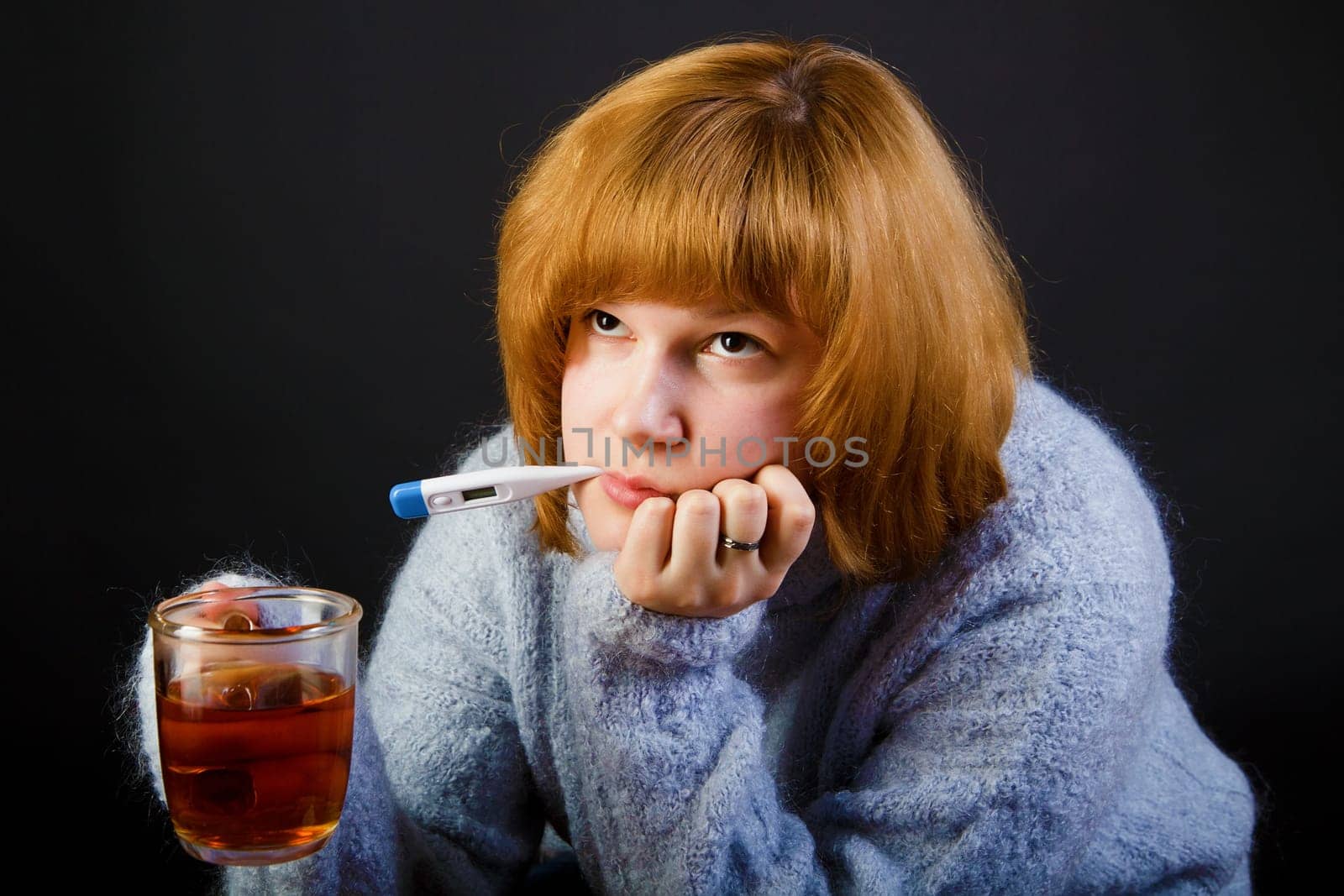 sick girl with tea and a thermometer on a black background