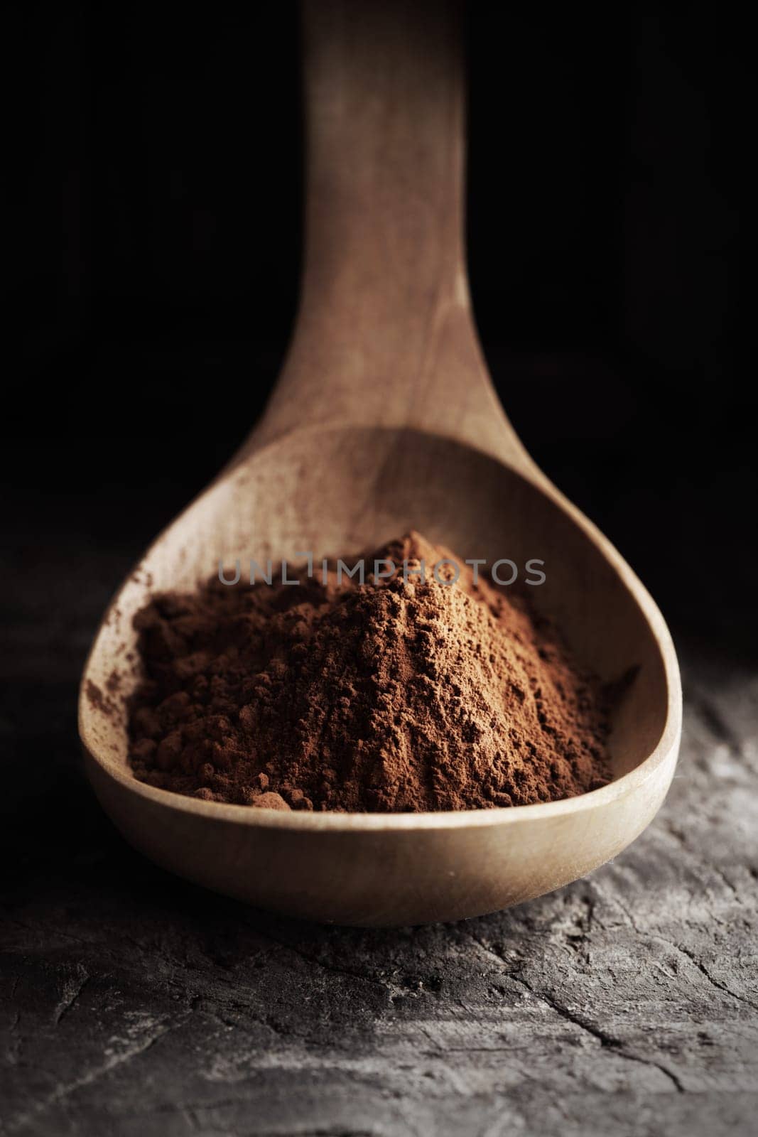 Wooden spoon full of cocoa powder