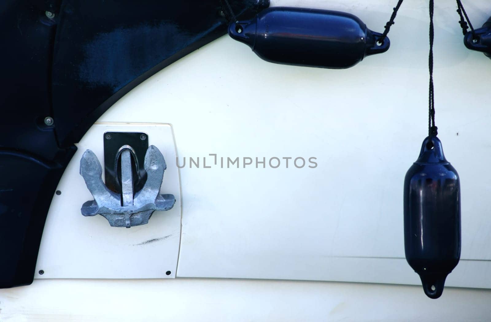 The side view of a motorboat with a ship anchor and floating buoys.