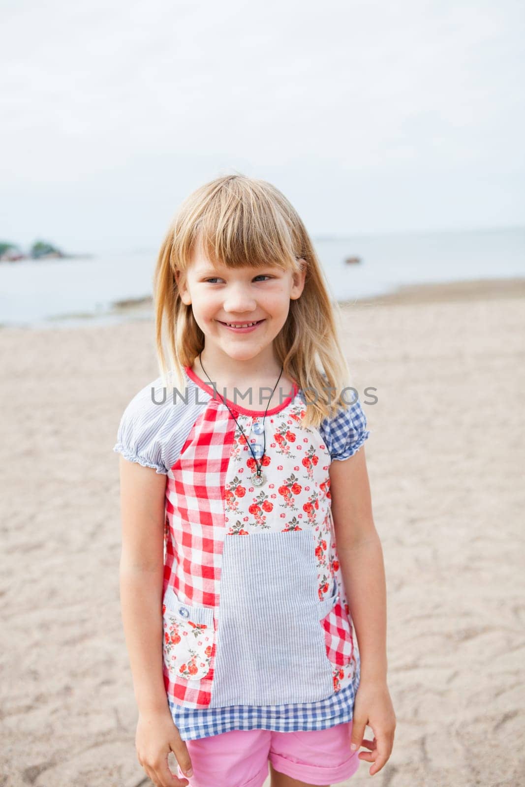 Smiling cute young girl at beach looking to side with ocean in background