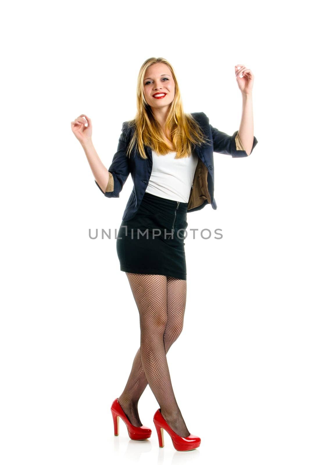 Attractive young girl wearing black miniskirt und red high heels and dancing isolated against white background.