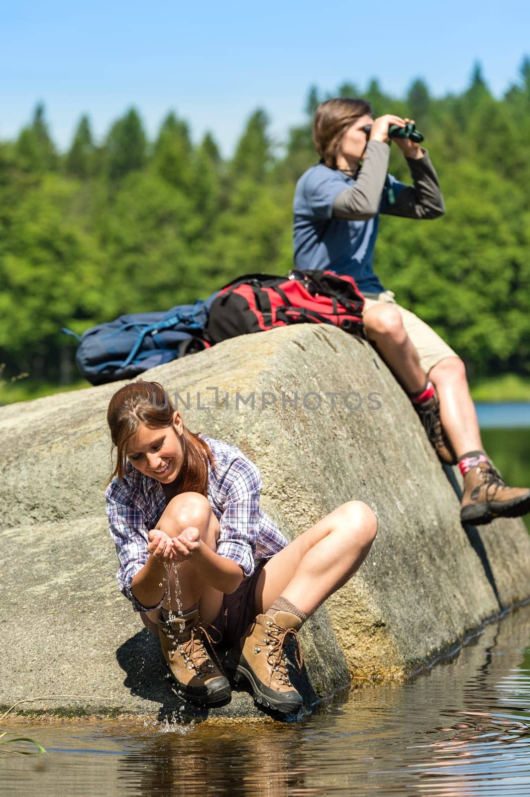 Teenagers resting and birdwatching by lake young hikers sporty