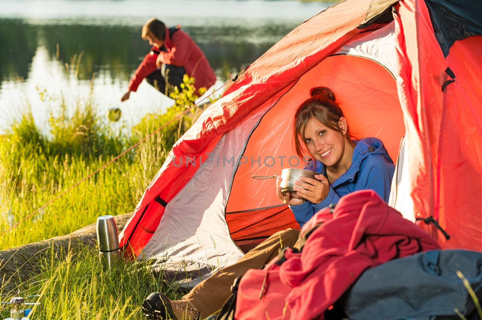 Camping girl sitting in tent drinking from pot