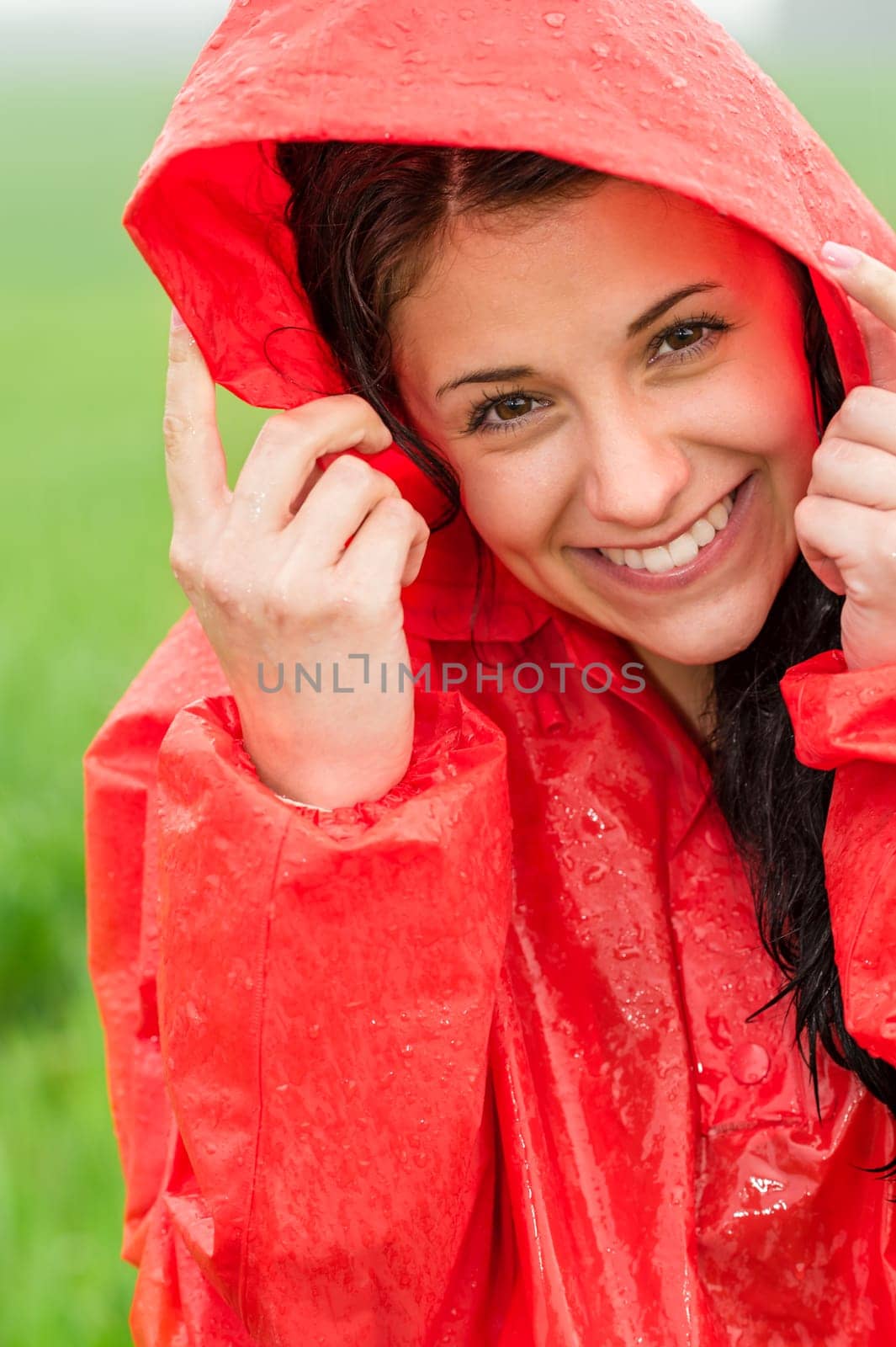 Portrait of cheerful teenager in the rain in red raincoat
