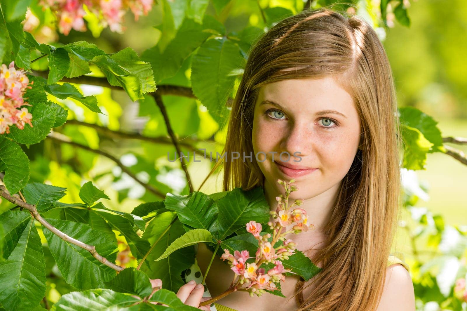 Girl in the sunshine smelling tree blossom in springtime