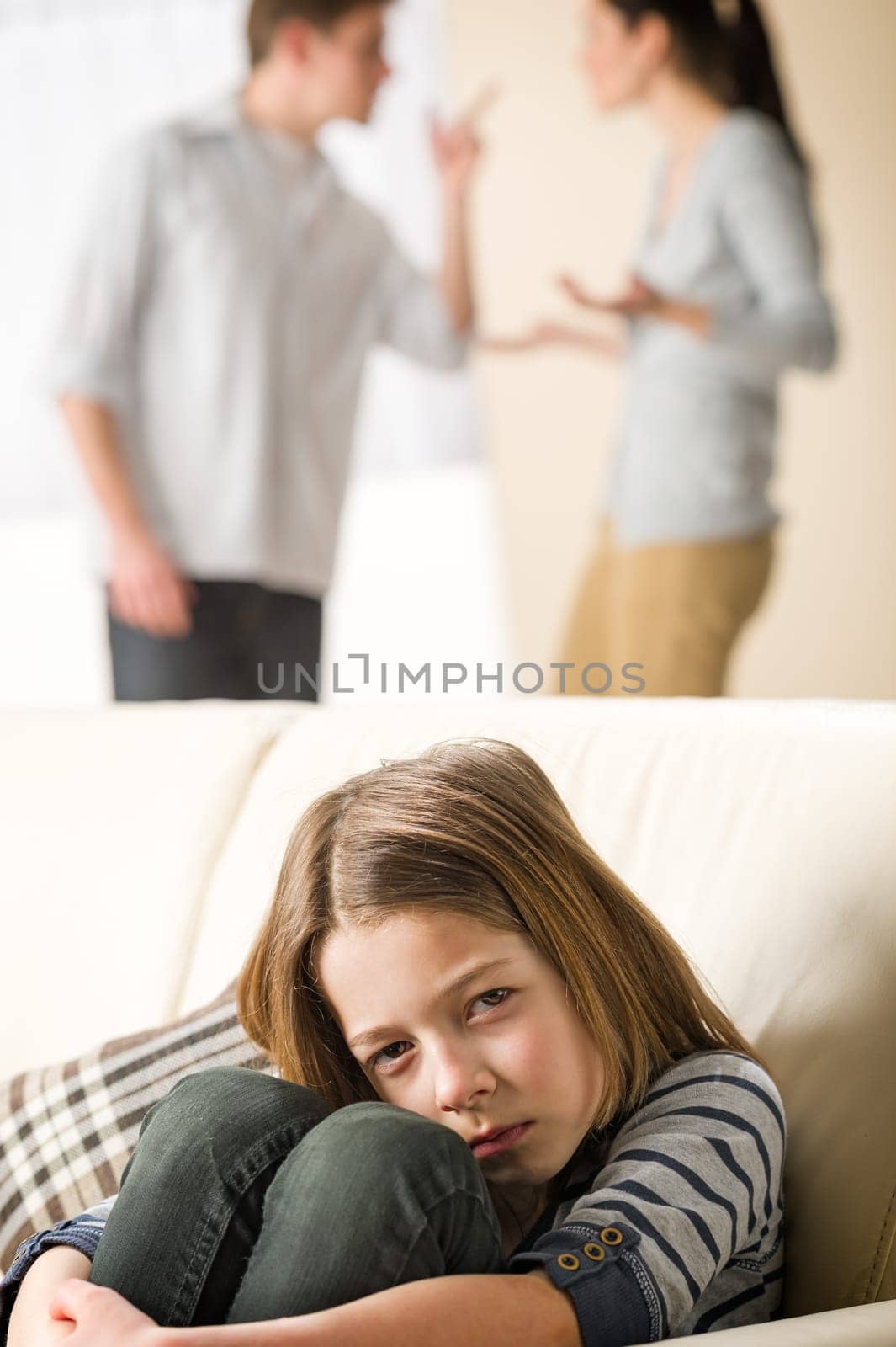 Sad little girl and fighting parents in the background