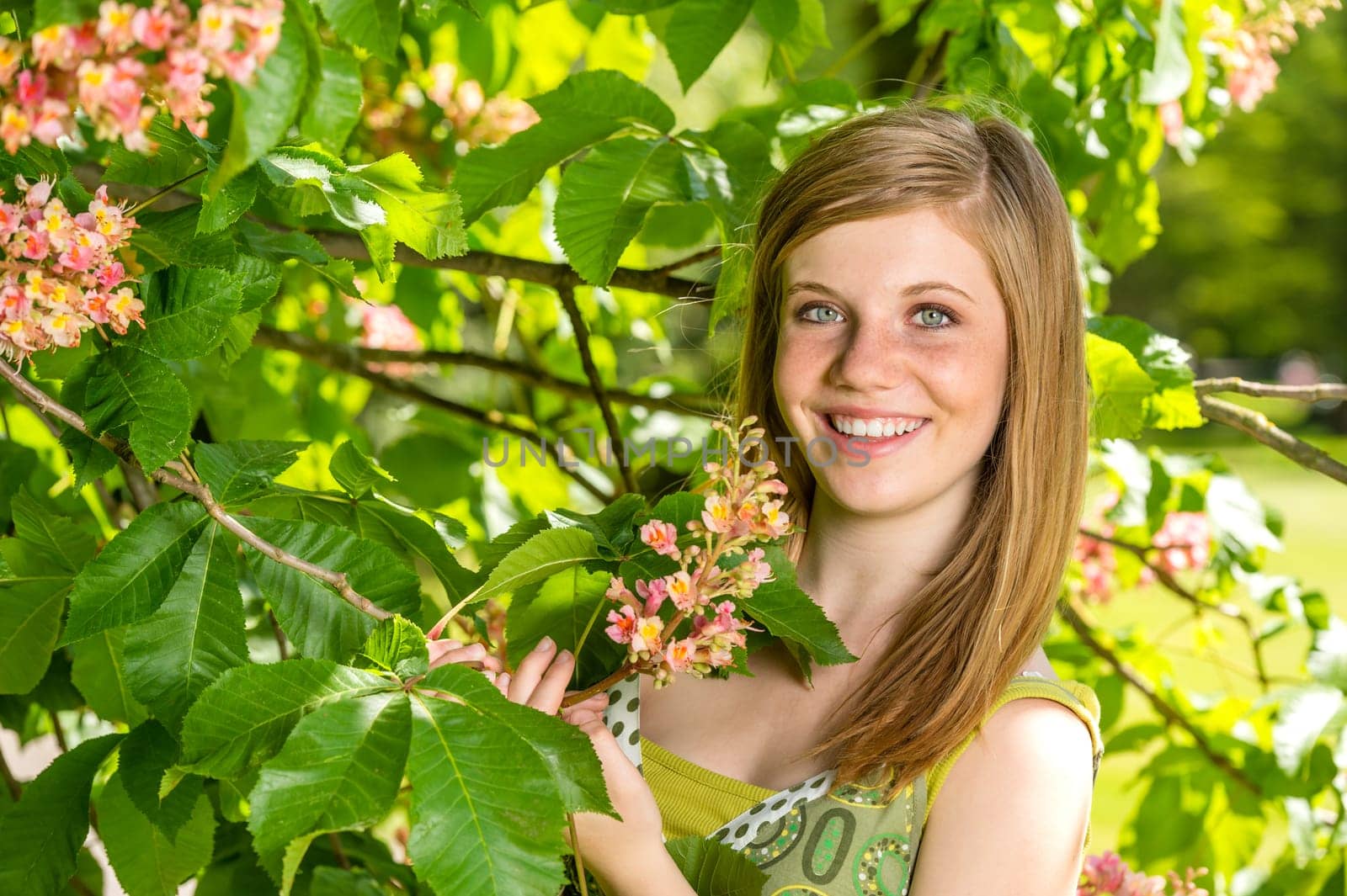 Portrait of young girl holding blossom in sunny park spring