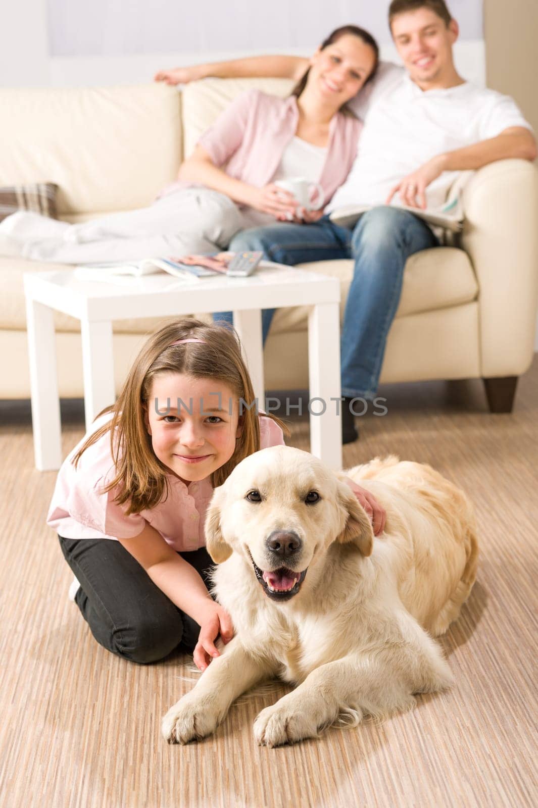 A happy family of three sitting with dog