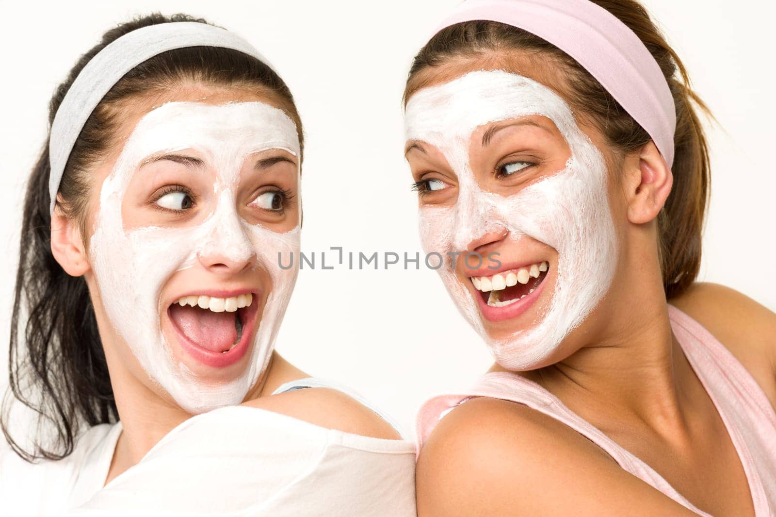 Cheerful girls having facial mask and laughing at each other