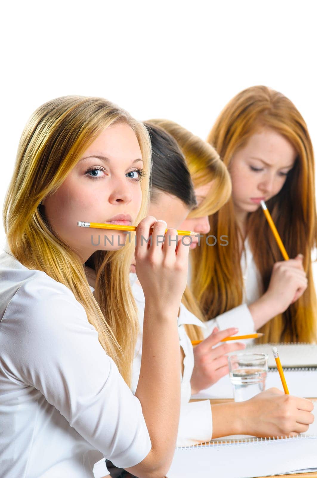 pretty female college student sitting an exam in a classroom full of students