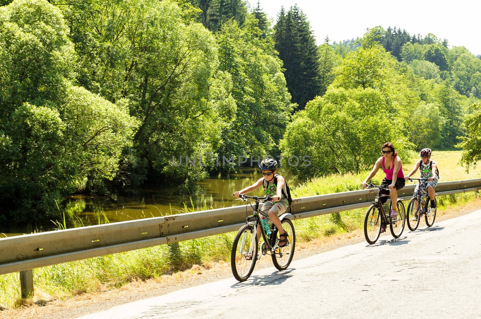 Mother with two sons riding bicycle on trip in sunny day