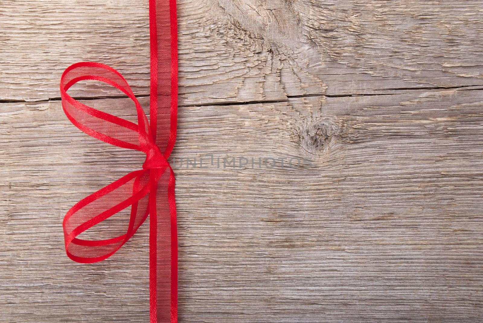 a red bow on a wooden background with copy space