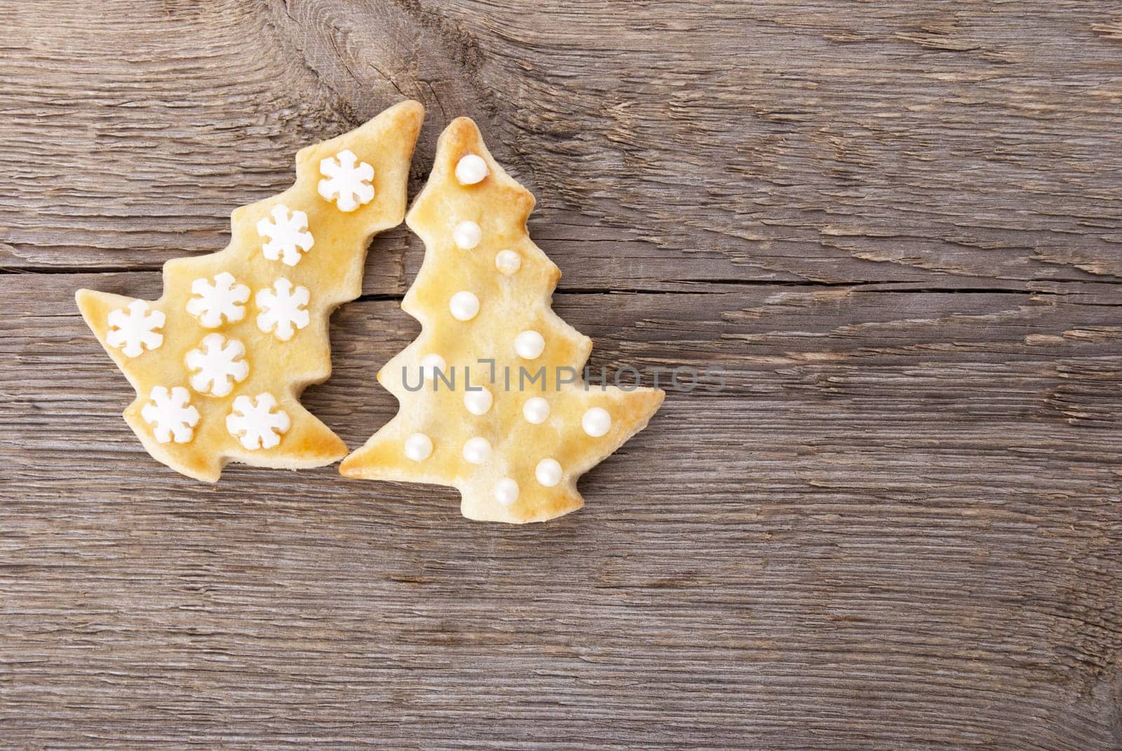 two christmas tree cookies ob a wooden background with copyspace