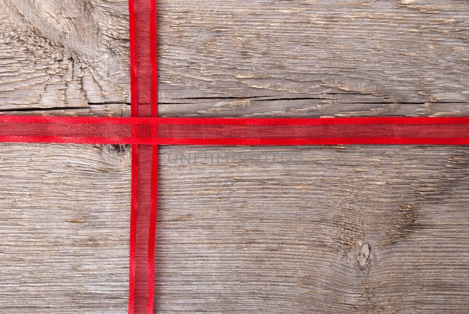 red ribbon on wood in shape of a cross with copy space as background
