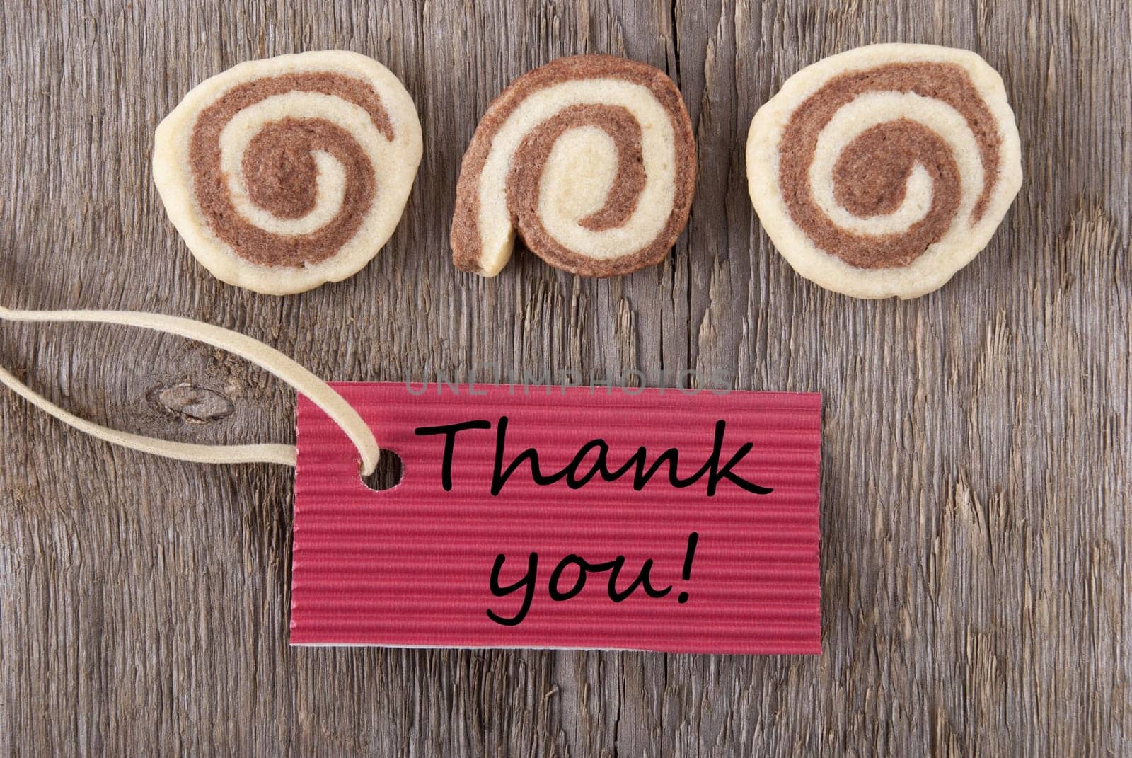 a red label with thank you on it with cookies on a wooden background