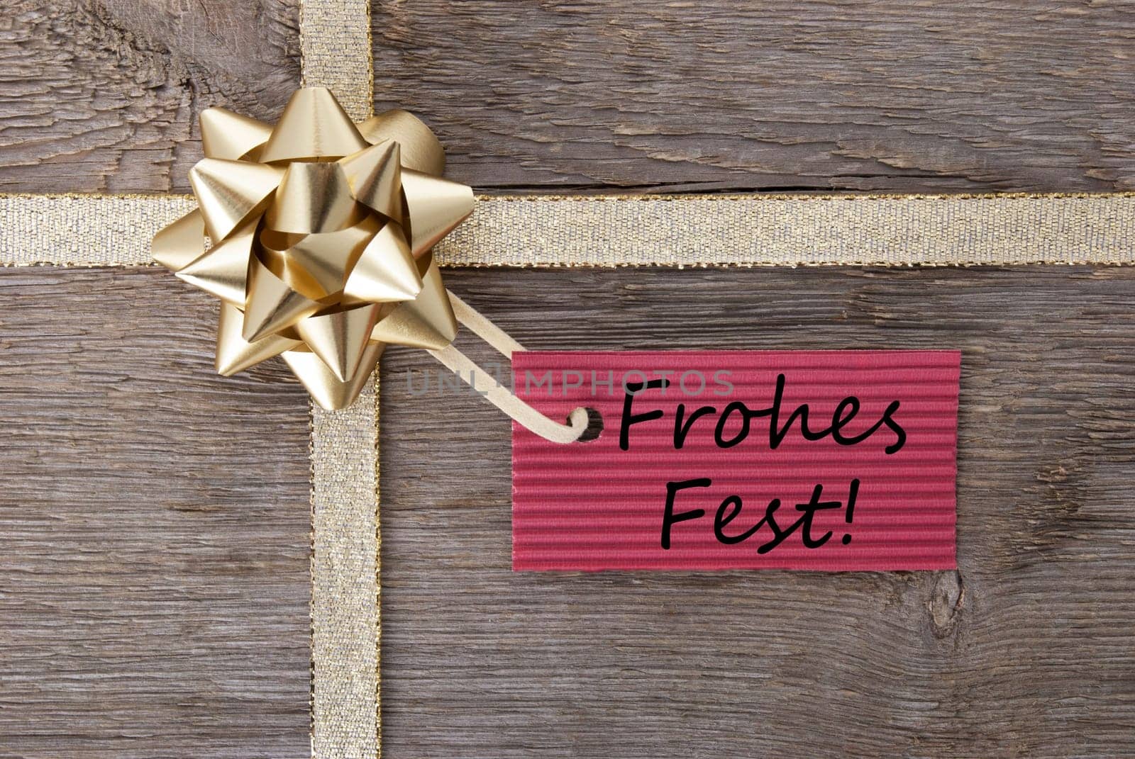 the german words Frohes Fest which means merry christmas on a red label on a golden bow as present