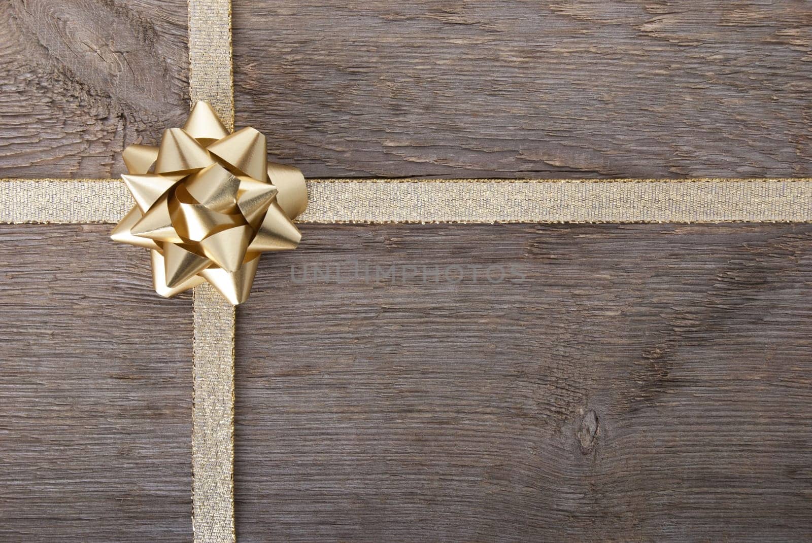 a golden bow on golden ribbon on wood as background with copy space