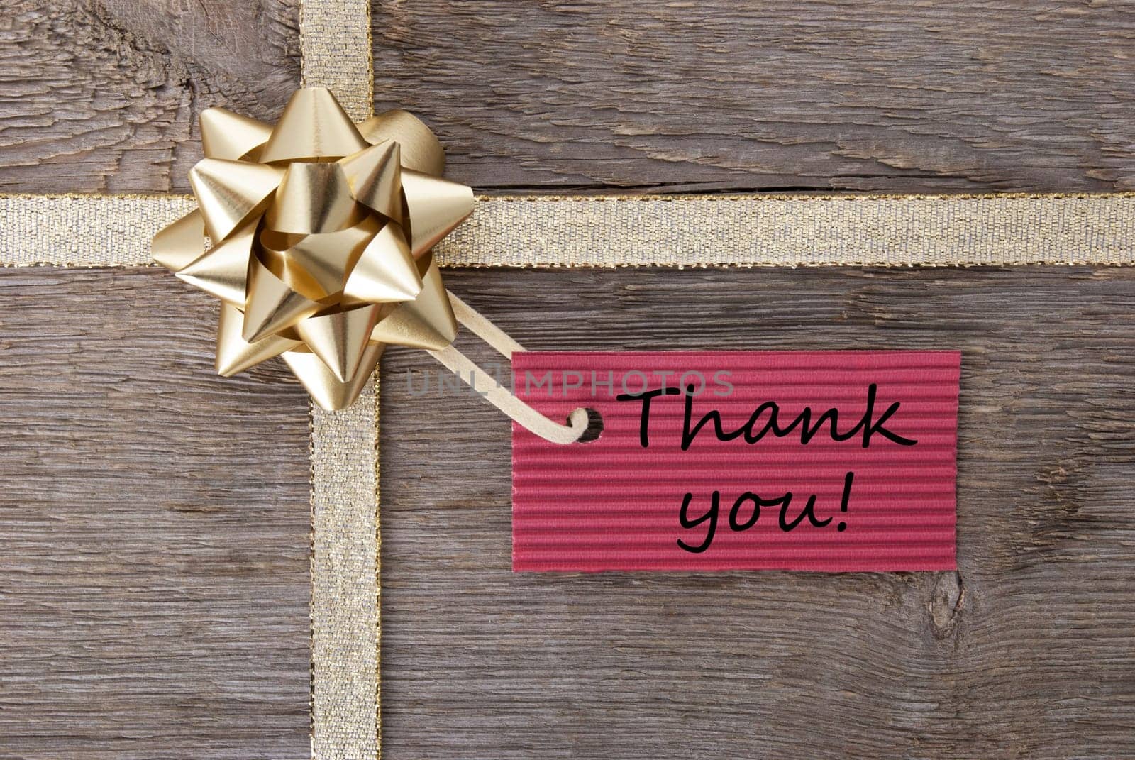thank you on a red label on a golden gift bow as present background