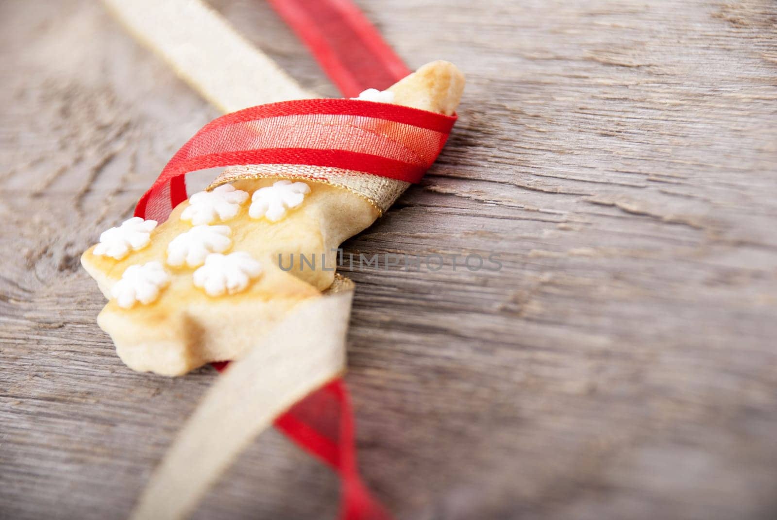 a christmas tree cookie in red and golden ribbon as ornamentation