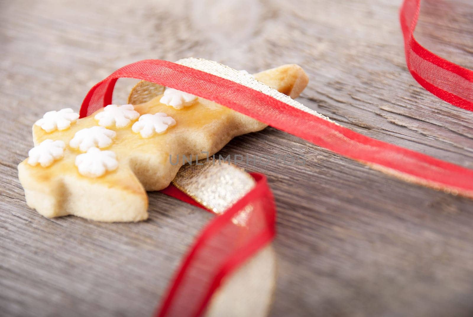 a christmas tree cookie in red and golden ribbon as christmas background