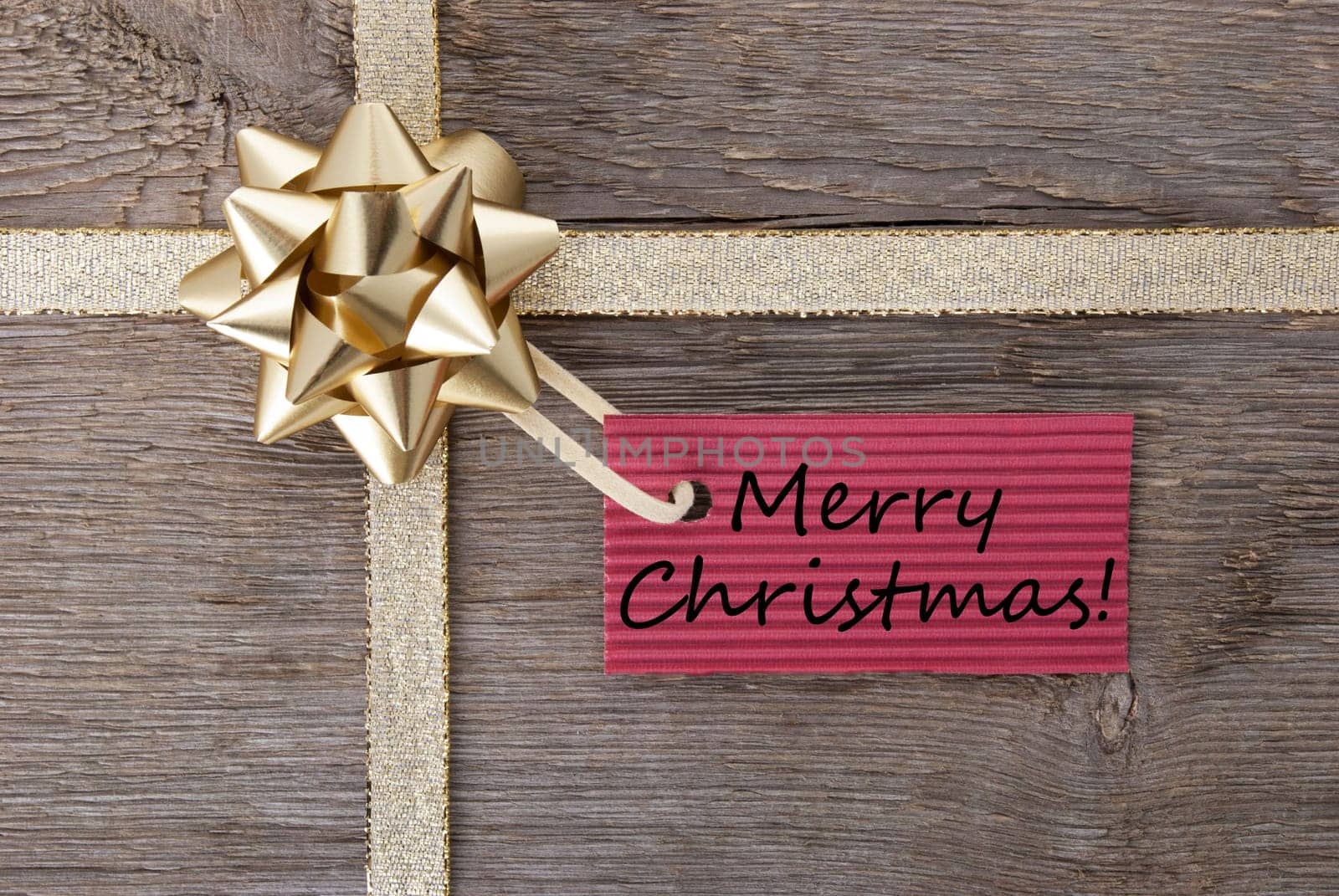 merry christmas on a red label on a golden bow, christmas background