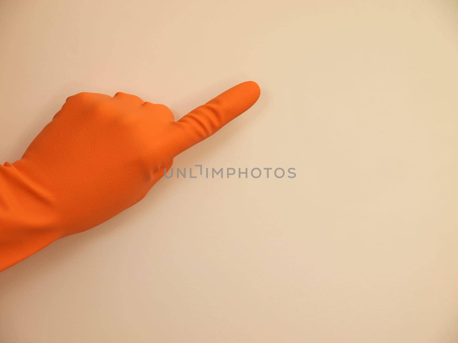 Hand with a rubber glove pointing on something, background with space for text or image
