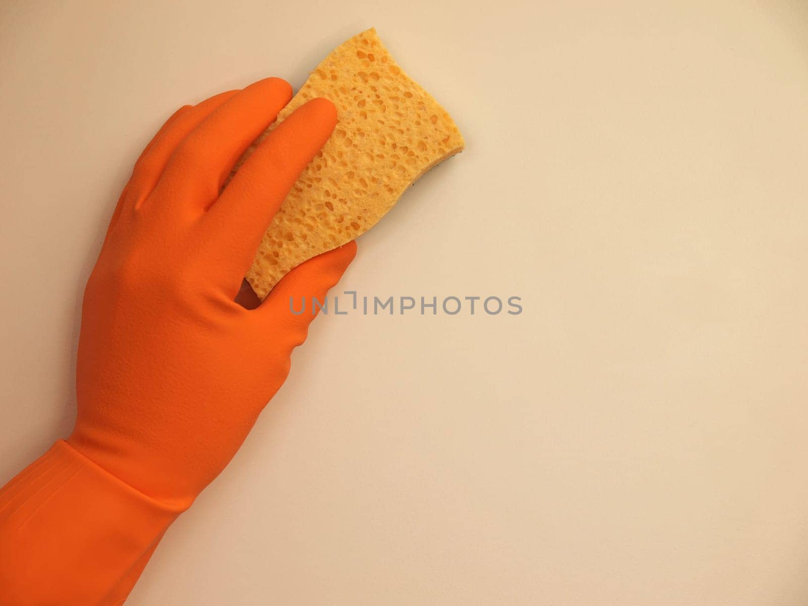 Hand with a rubber glove cleaning a surface