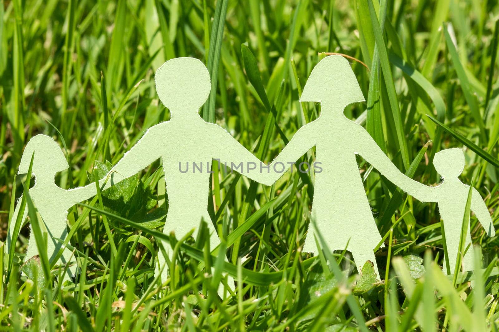 Paper family on  green grass in a bright day