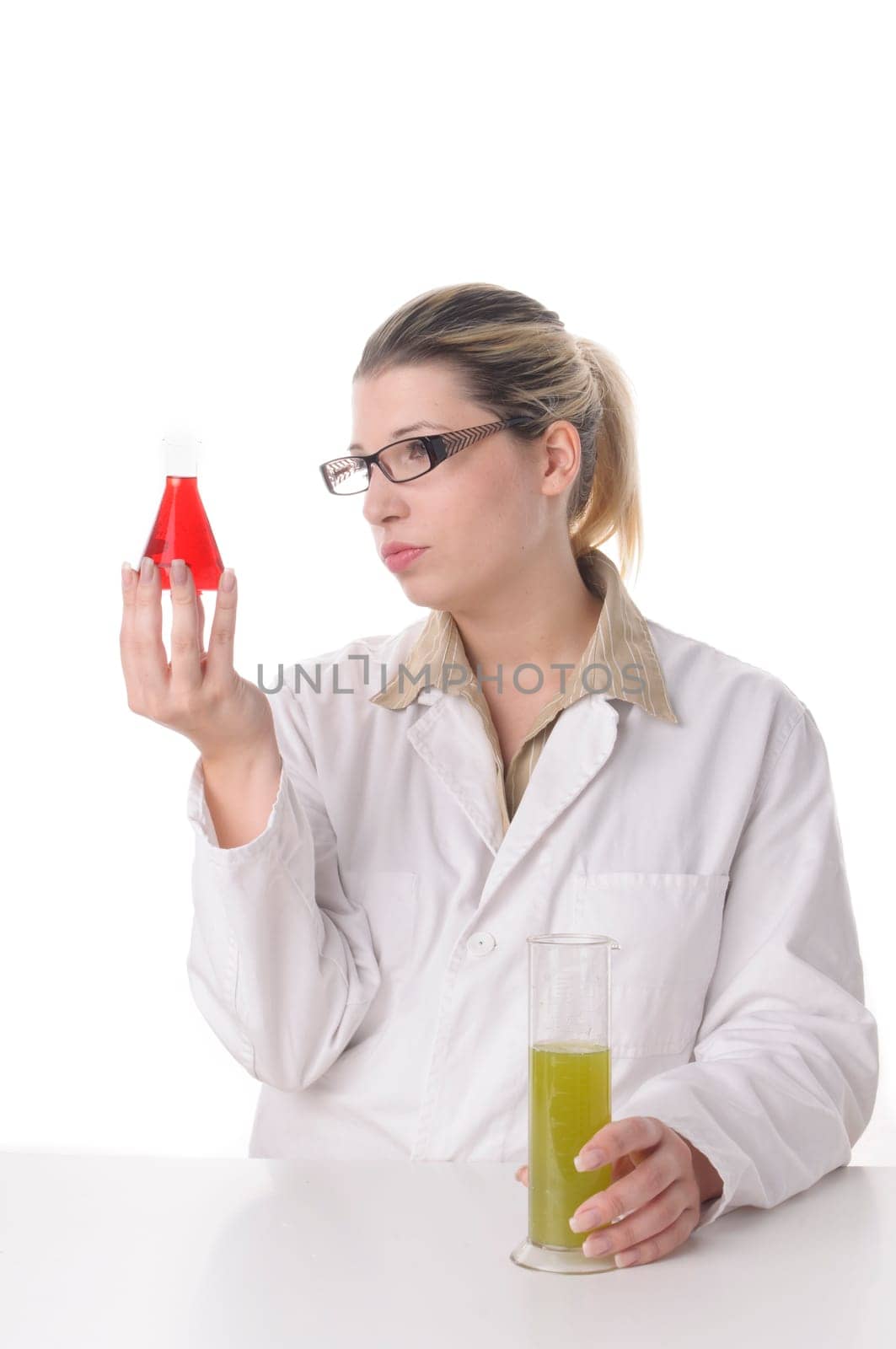 attractive young chemical laboratory assistant with blond hair and glasses works with various coloured liquids in test tubes,exposed against a white background