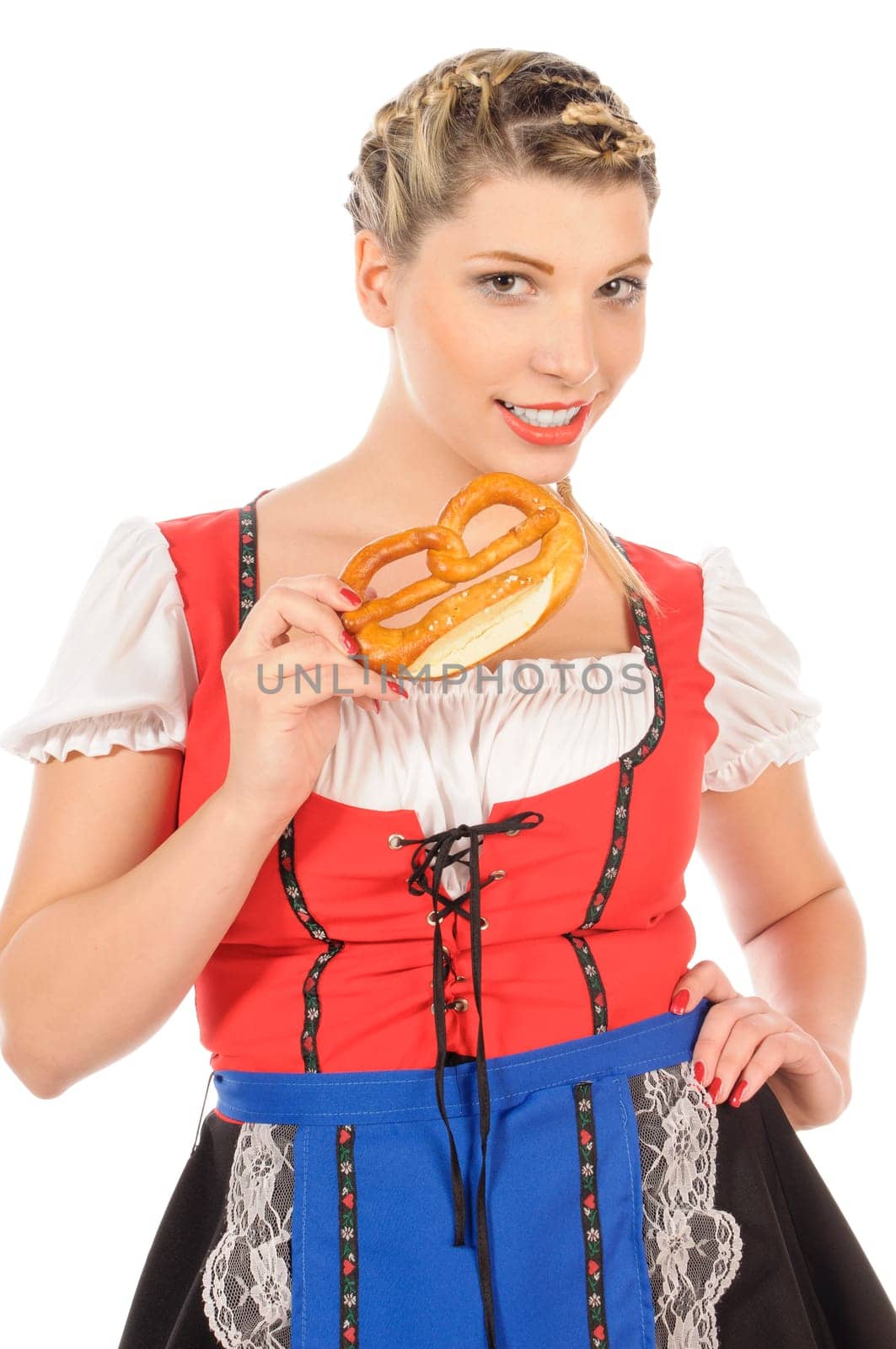 Young attractive woman with blond hair and braids wears a colorful dirdl dress and holds a pretzel in her hand,exposed against a white background.