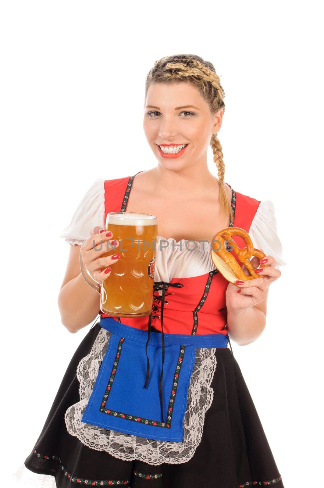 Young attractive woman with blond hair and braids wears a colorful dirdl dress and holds a pretzel and a beer mug with freshly tapped beer in her hand,exposed against a white background.