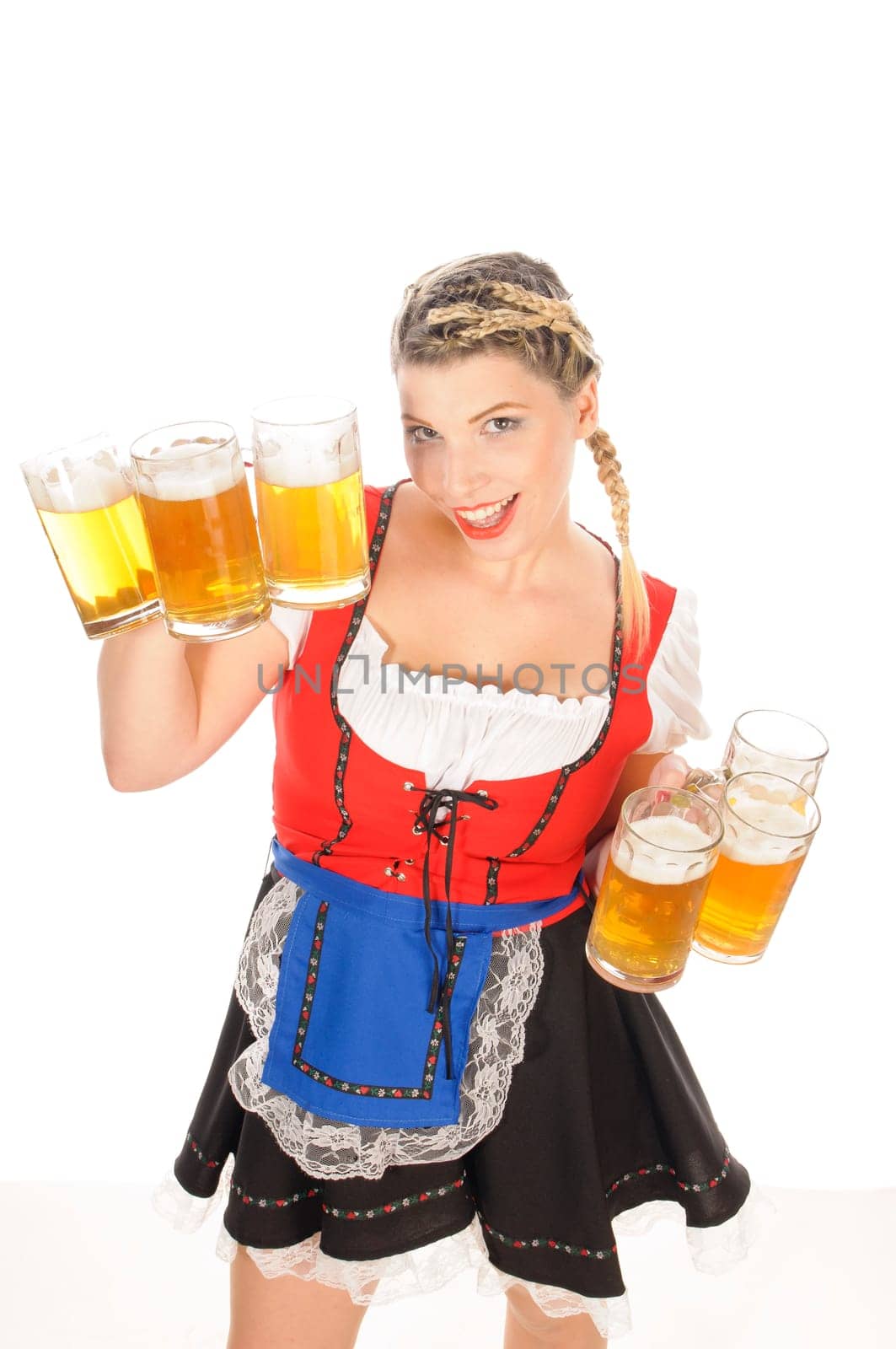 Young attractive woman with blond hair and braids wears a colorful dirdl dress and holds several full beer mugs with freshly tapped beer in her hand,exposed against a white background.