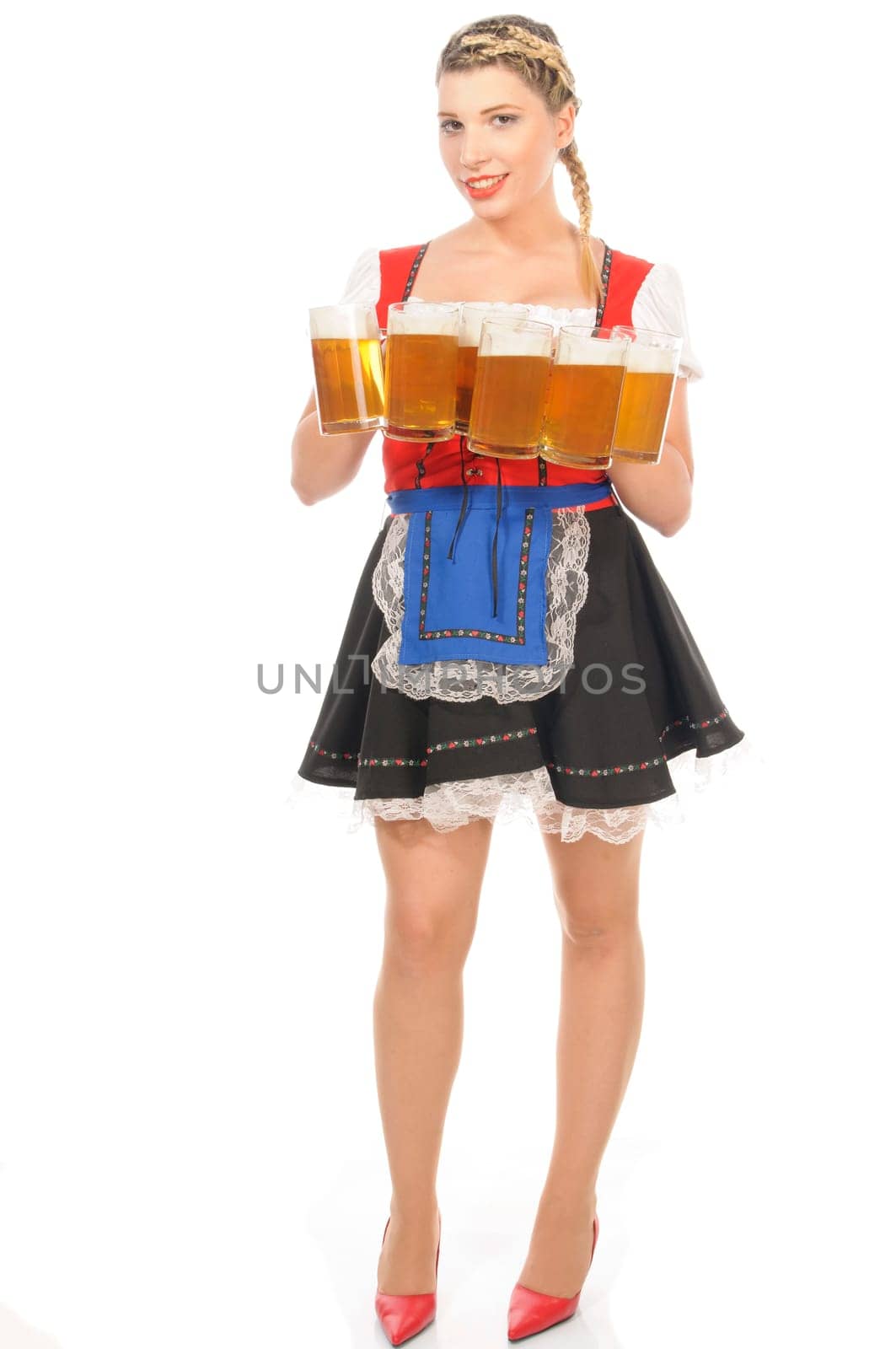 Young attractive woman with blond hair and braids wears a colorful dirdl dress and holds several full beer mugs with freshly tapped beer in her hand,exposed against a white background.